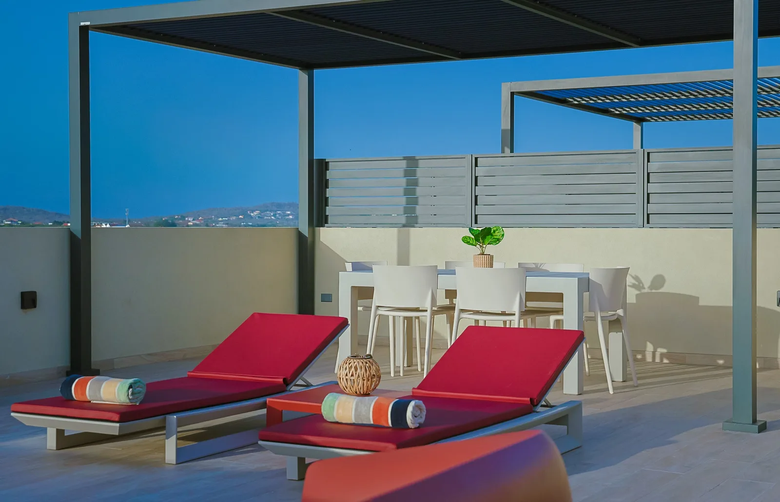 Unwind on your private terrace with comfortable loungers, a shaded pergola, and an outdoor dining area perfect for sun-soaked afternoons and warm evenings under the sky.