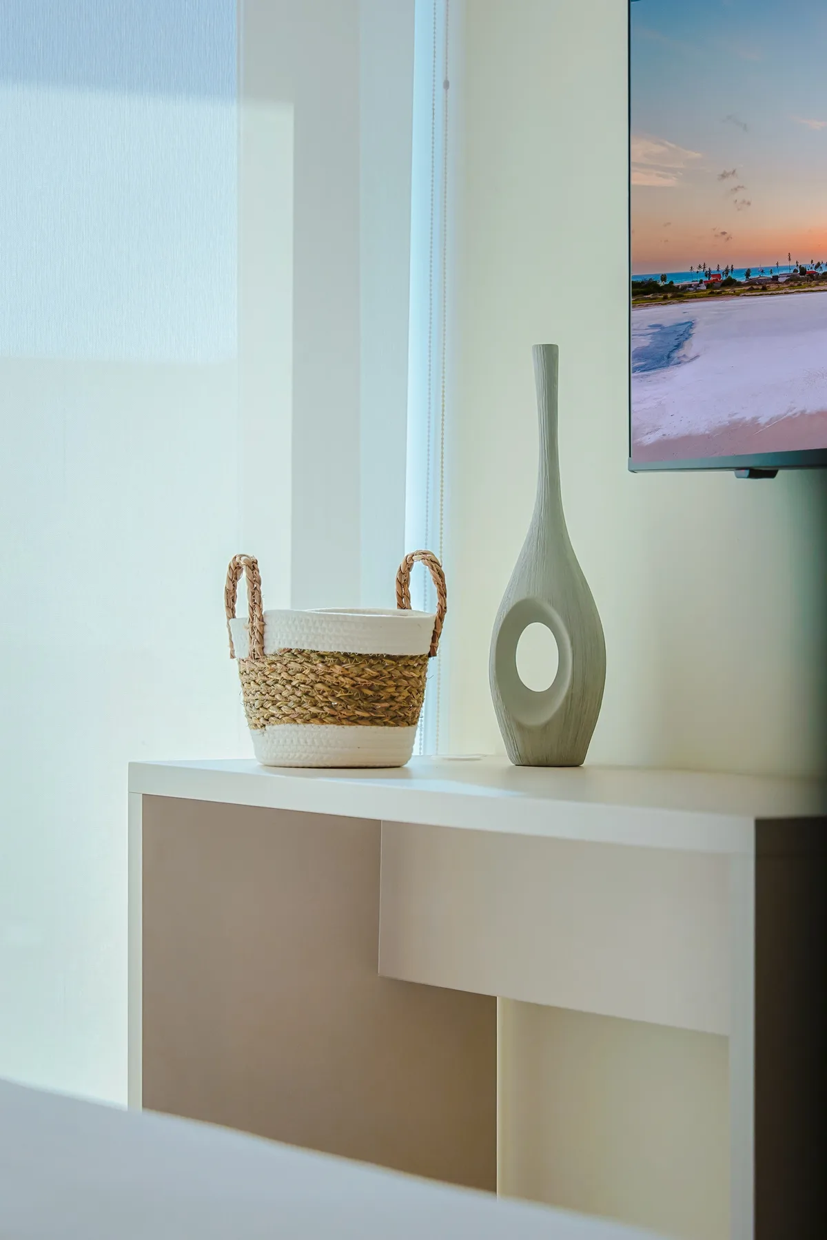 A coastal sunset graces the screen above your entertainment console, where simple decor brings a beachy, calming vibe to your relaxing evenings indoors.