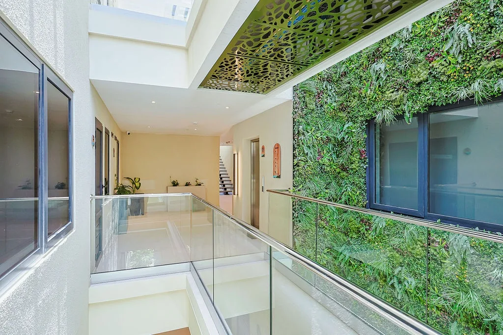 A bright, modern hallway connects you to your space, with a stunning living plant wall and dramatic decorative ceiling bringing nature and artistry indoors.