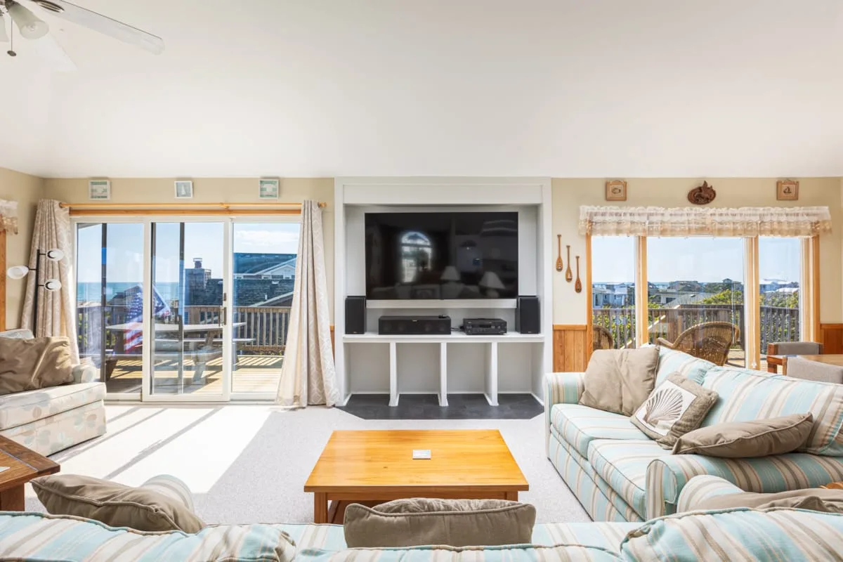 A bright living room with seating, a coffee table, and a television.