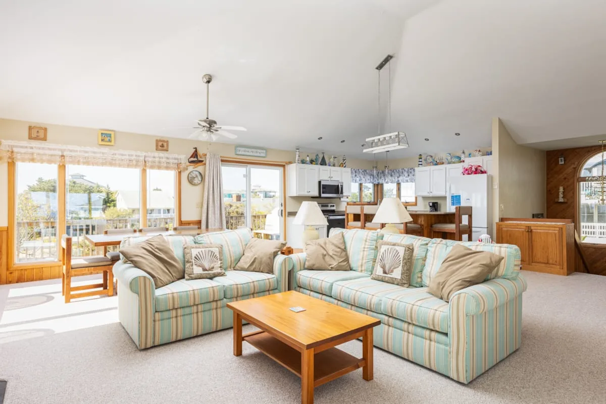 A bright living room with striped seating and a wooden coffee table.