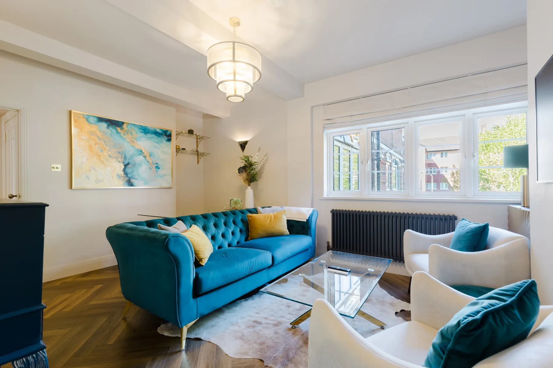 A bright living room with teal seating arranged around a glass coffee table.