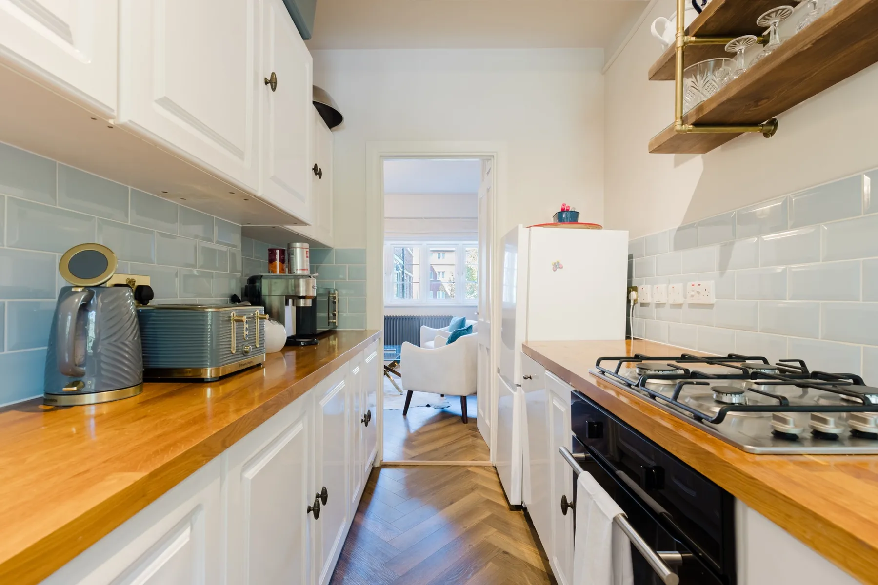 A narrow kitchen with wooden countertops and a gas cooktop.