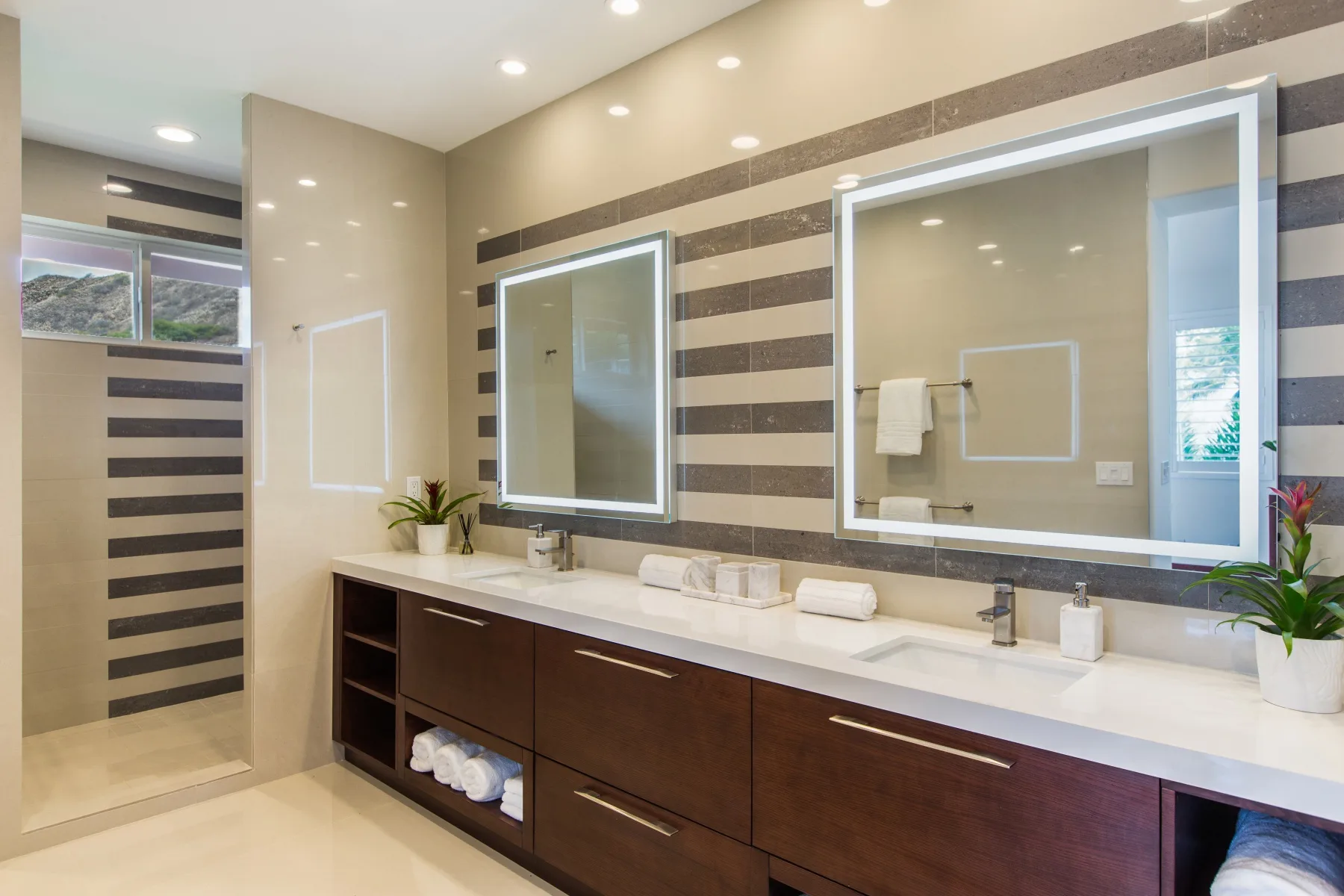 Un baño moderno con un tocador largo, dos lavabos y una ducha de vidrio.