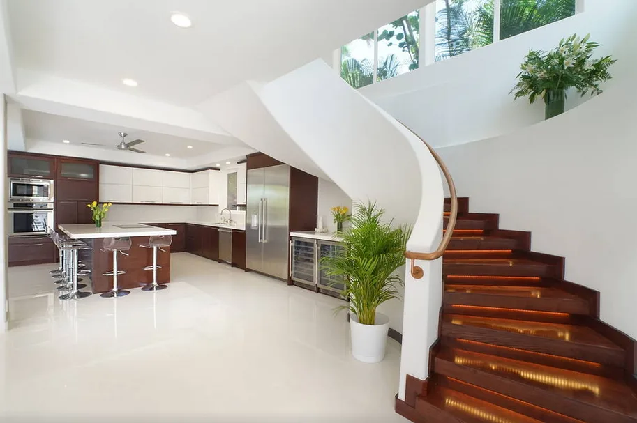 Una luminosa cocina abierta con comedor está junto a una escalera curva.