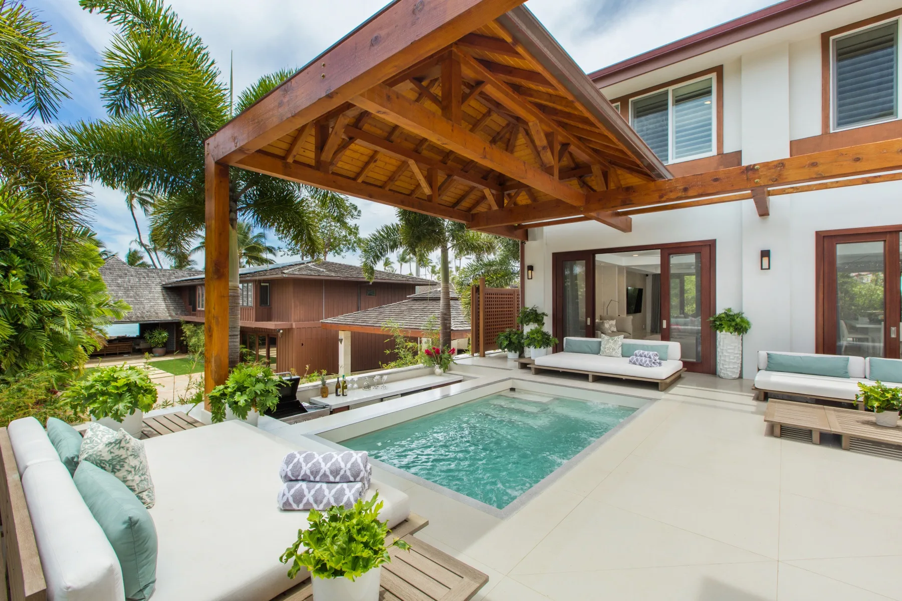 Patio con piscina y asientos bajo una pérgola de madera junto a la casa.