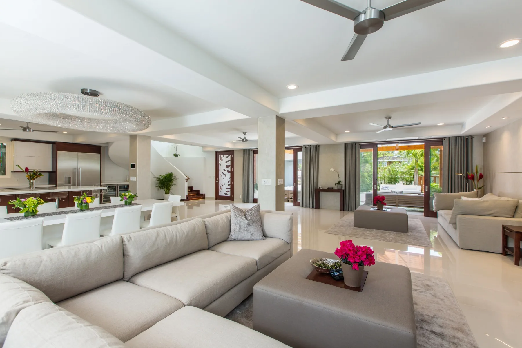 Una amplia sala de estar y comedor con asientos claros y una mesa con flores.