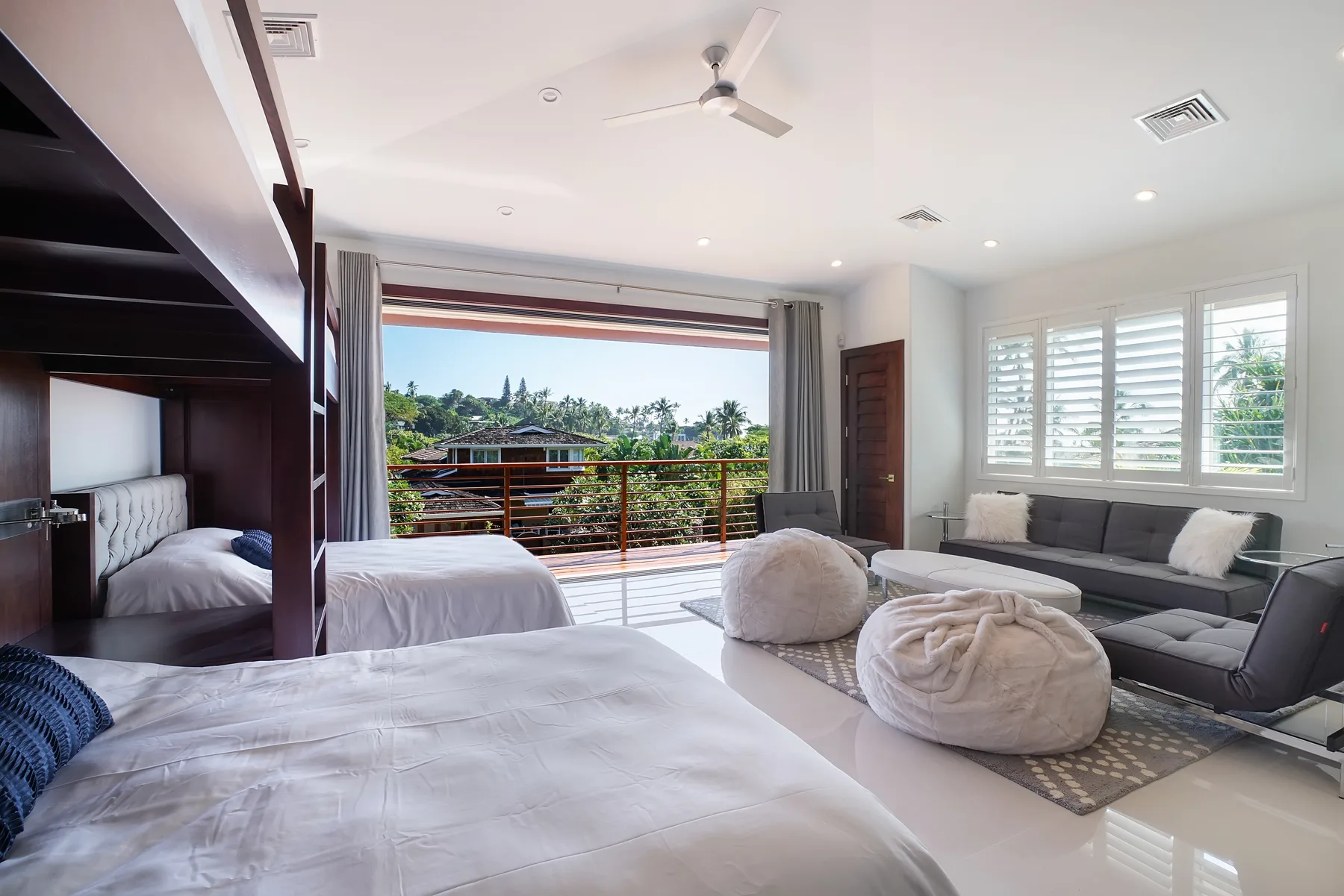 Un dormitorio luminoso da a un balcón, con una zona de estar junto a las ventanas.