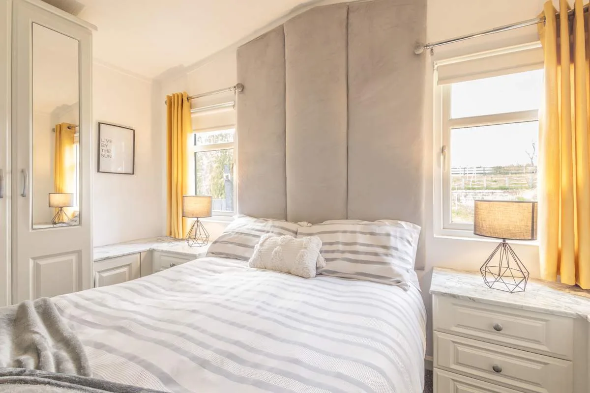 Un dormitorio luminoso con ropa de cama a rayas y cortinas amarillas.