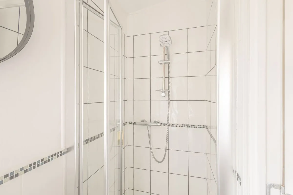 Ducha de baño con azulejos y una alcachofa de mano.