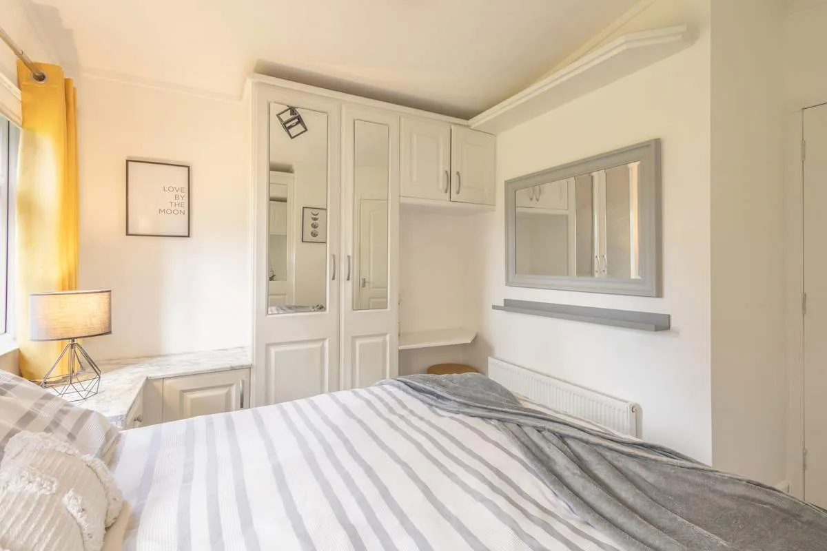 Un dormitorio con una cama, armarios empotrados y un espejo de pared.