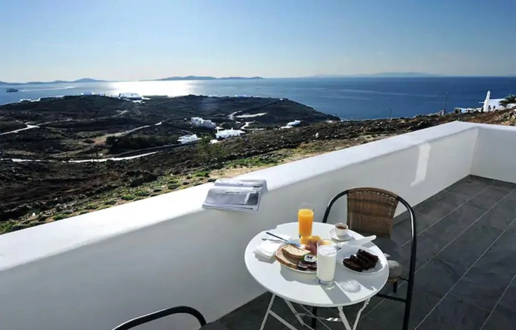Una terraza con una mesa pequeña y asientos mira hacia la costa y el mar.