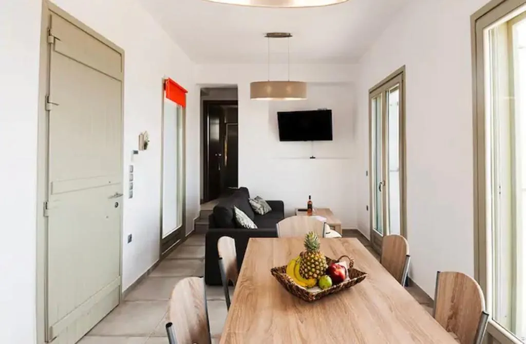 A dining area with a wooden table and seating, beside a living area with a sofa.