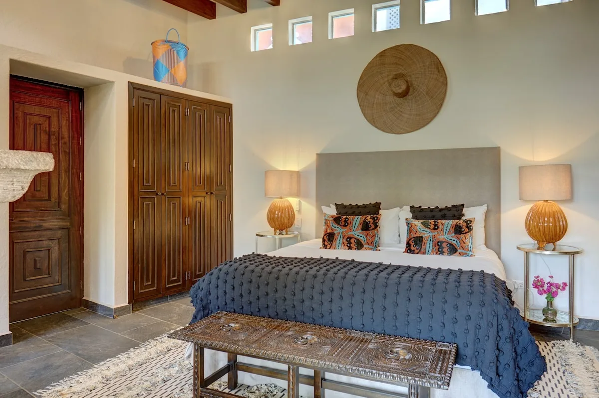 A bedroom with a large bed, patterned pillows, and matching bedside lamps.