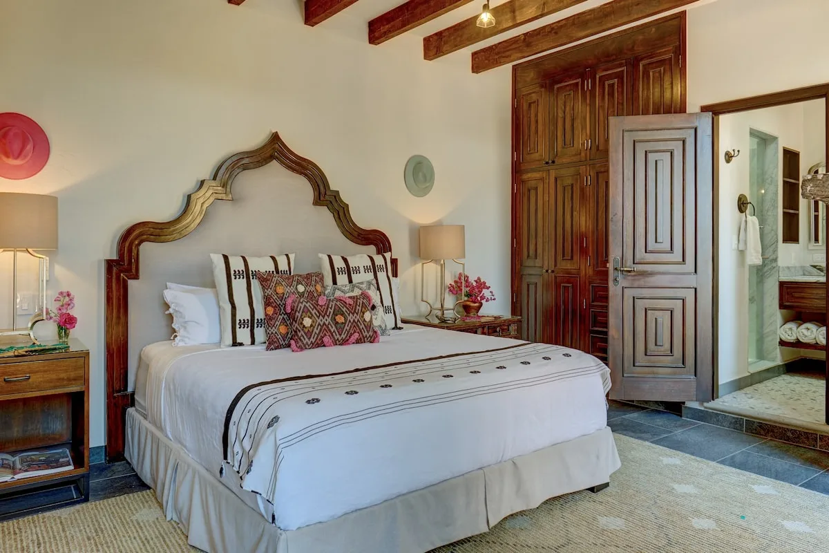 A bedroom with a large bed and an open doorway to a bathroom.