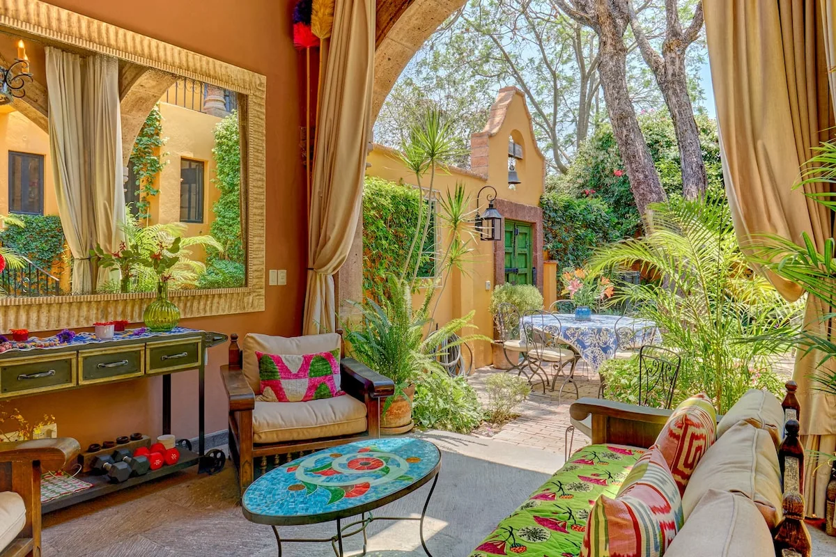 A furnished sitting area opens onto a leafy courtyard with a small outdoor table.