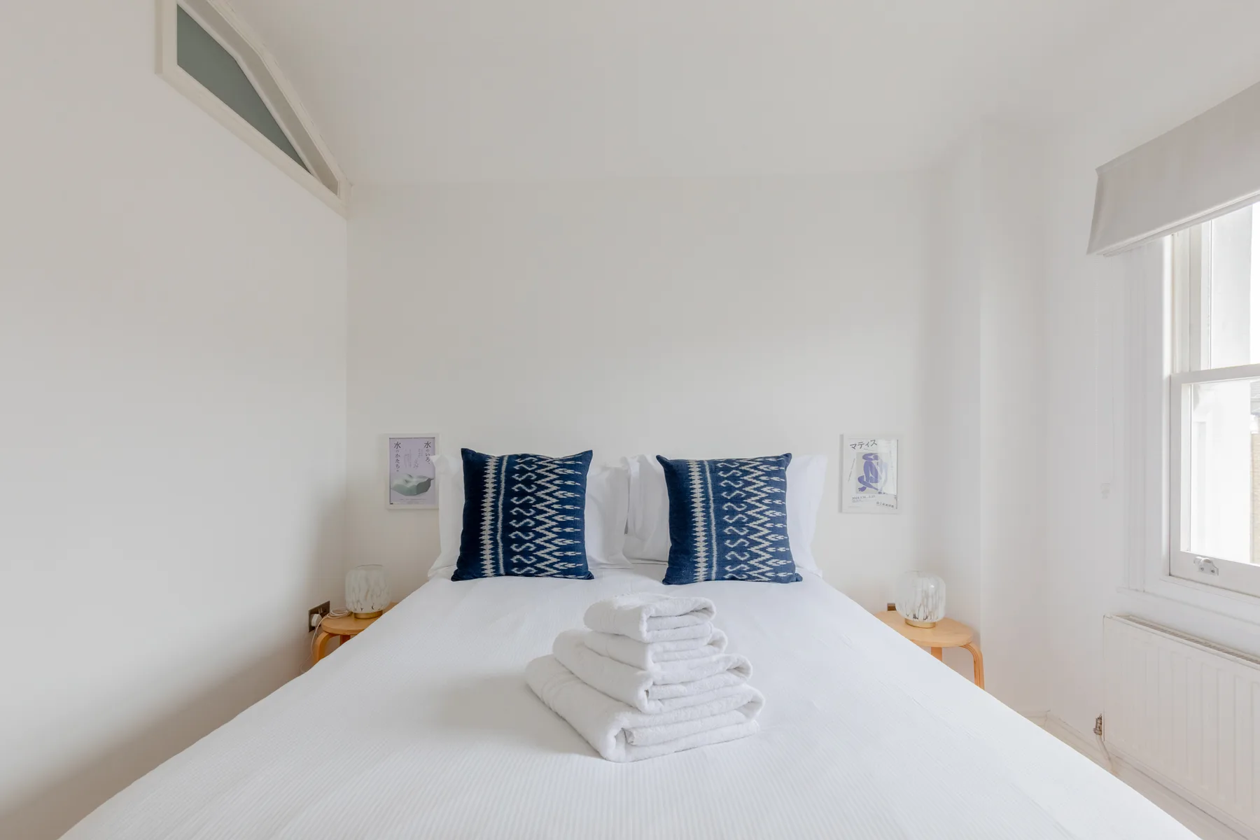A bedroom with a neatly made bed and two blue patterned pillows.