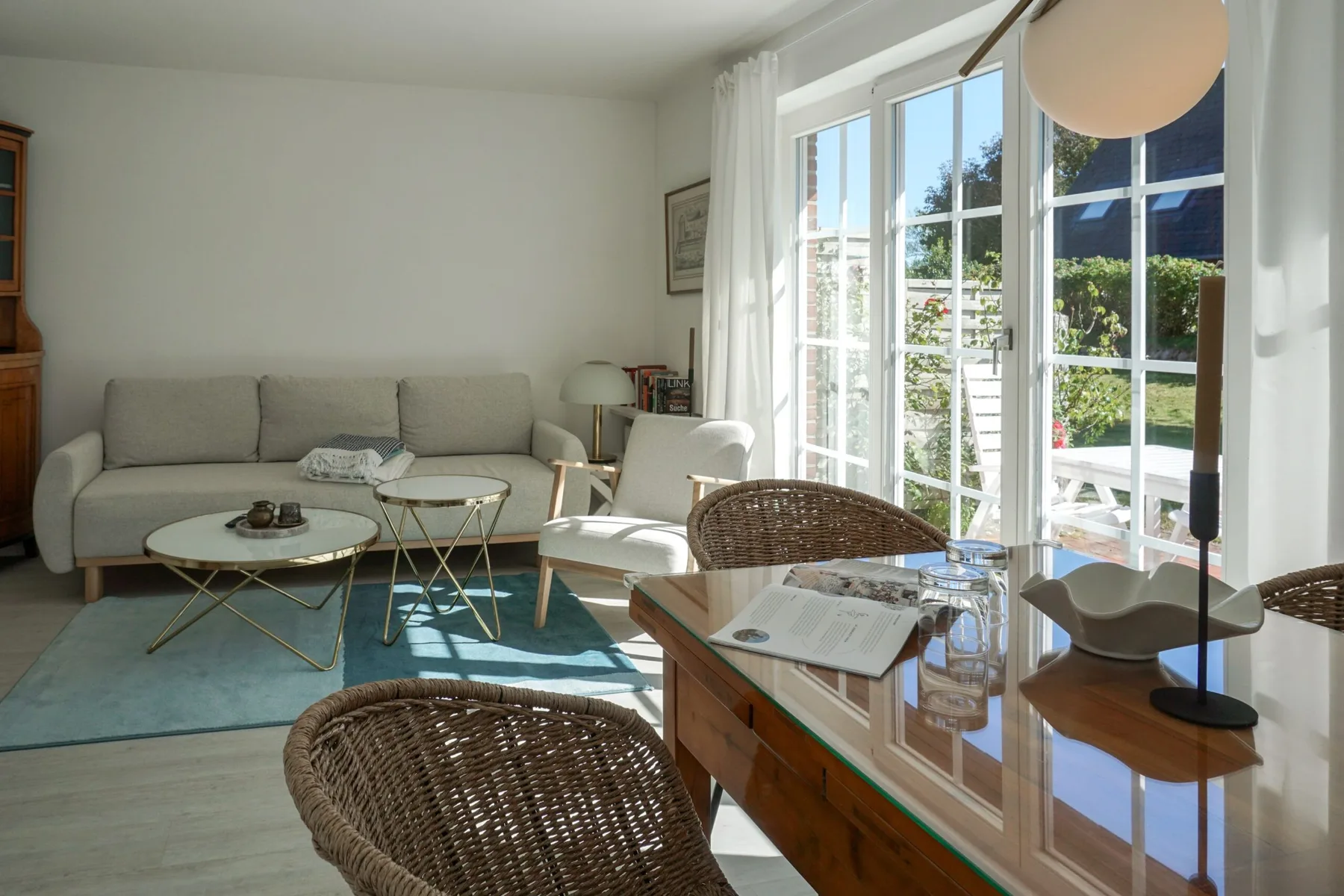 Una sala luminosa con asientos junto a grandes ventanales que dan a un jardín.