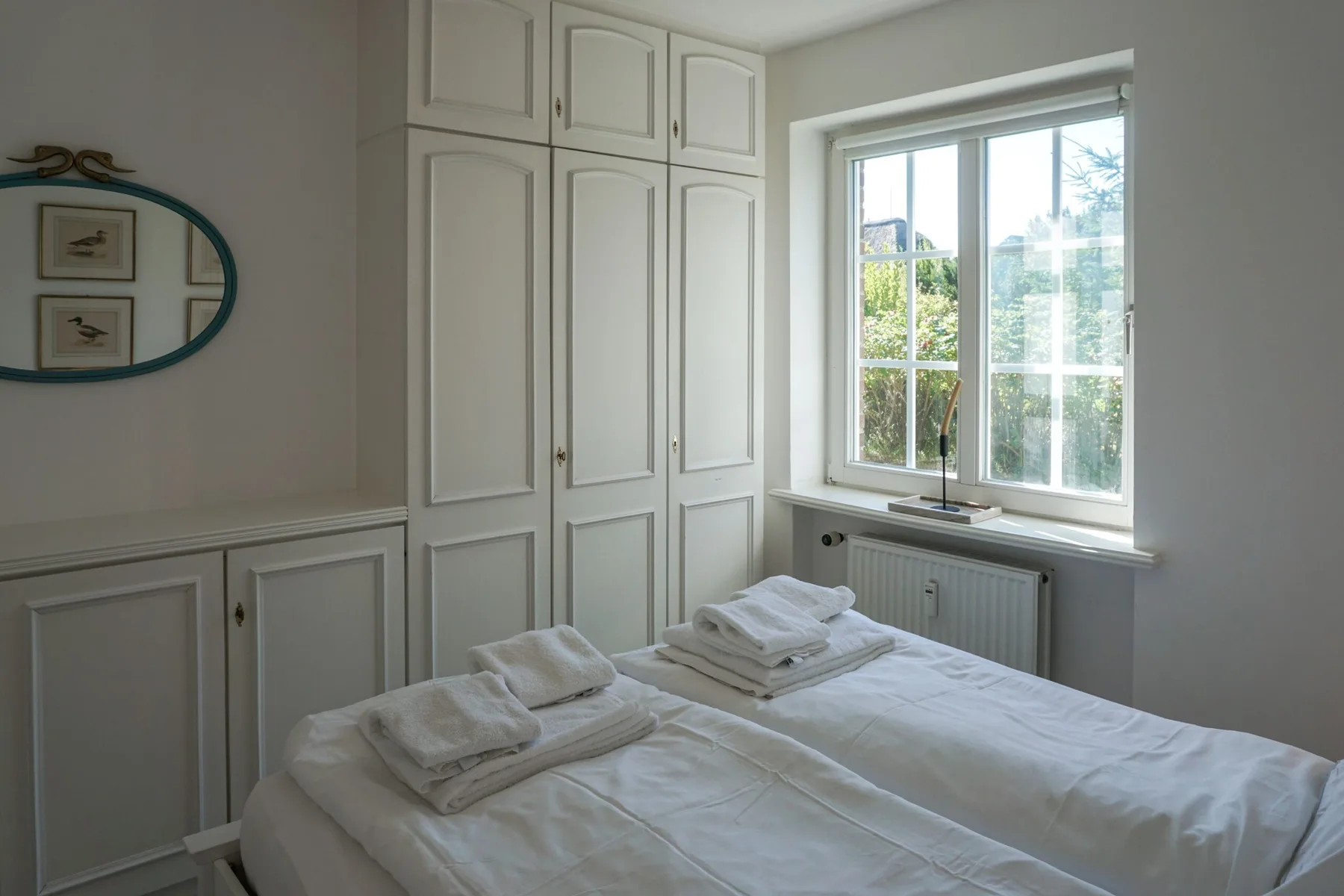 Un dormitorio luminoso con ropa de cama blanca junto a una ventana grande.
