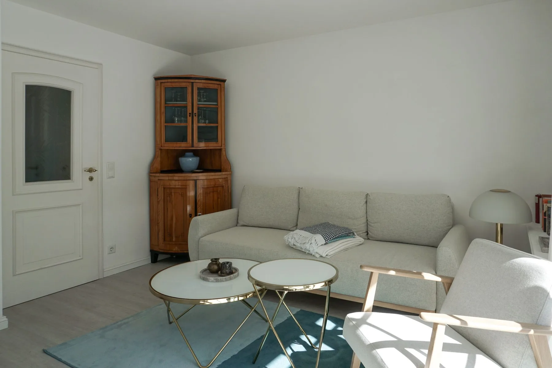 Una sala luminosa con un sofá seccional y mesas de centro con cubierta de vidrio.