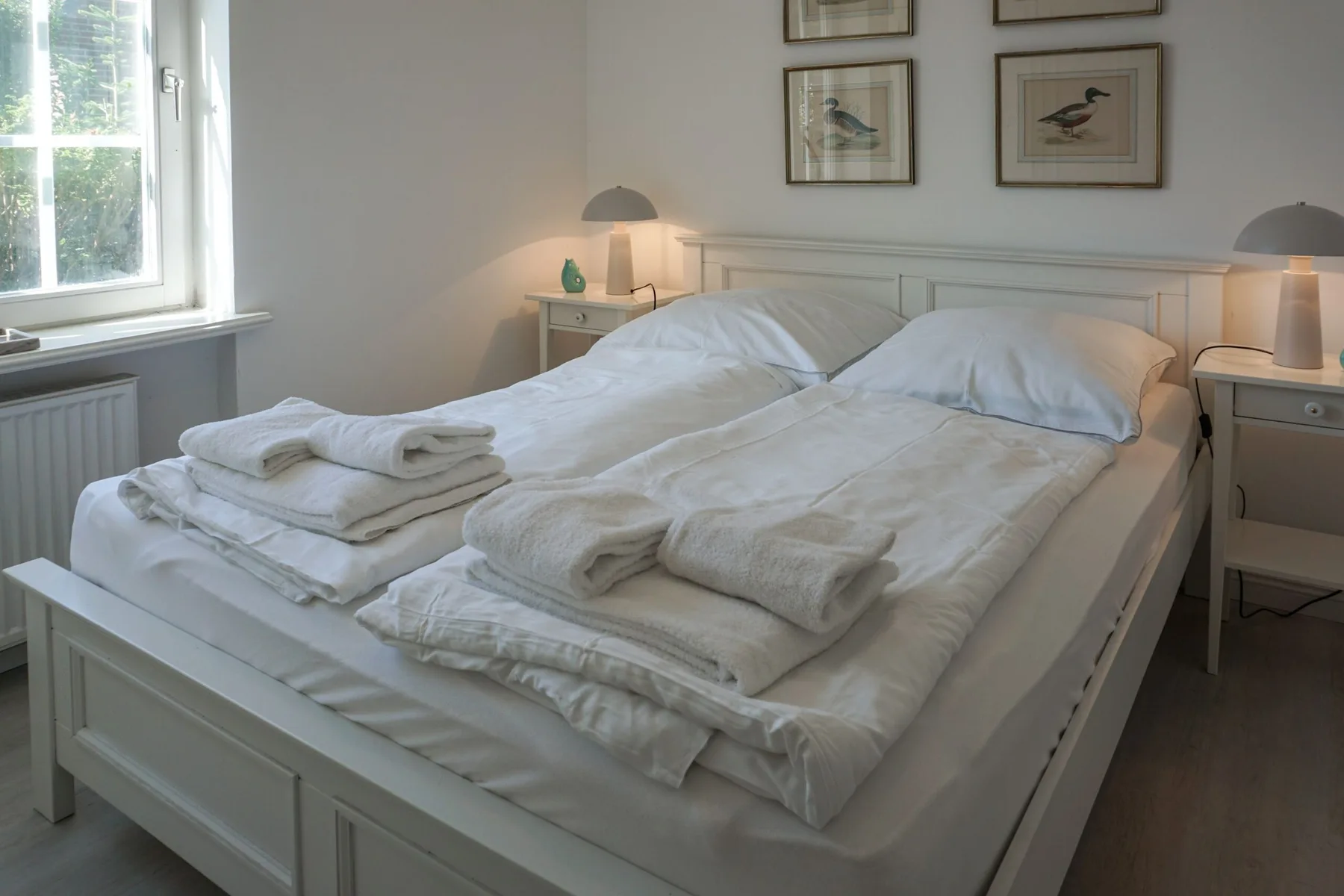 Un dormitorio con dos camas vestidas con sábanas blancas y toallas dobladas.