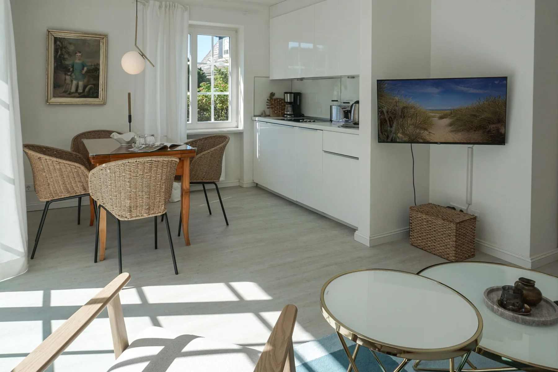 Una luminosa sala y comedor con mesa, asientos y una cocina compacta.