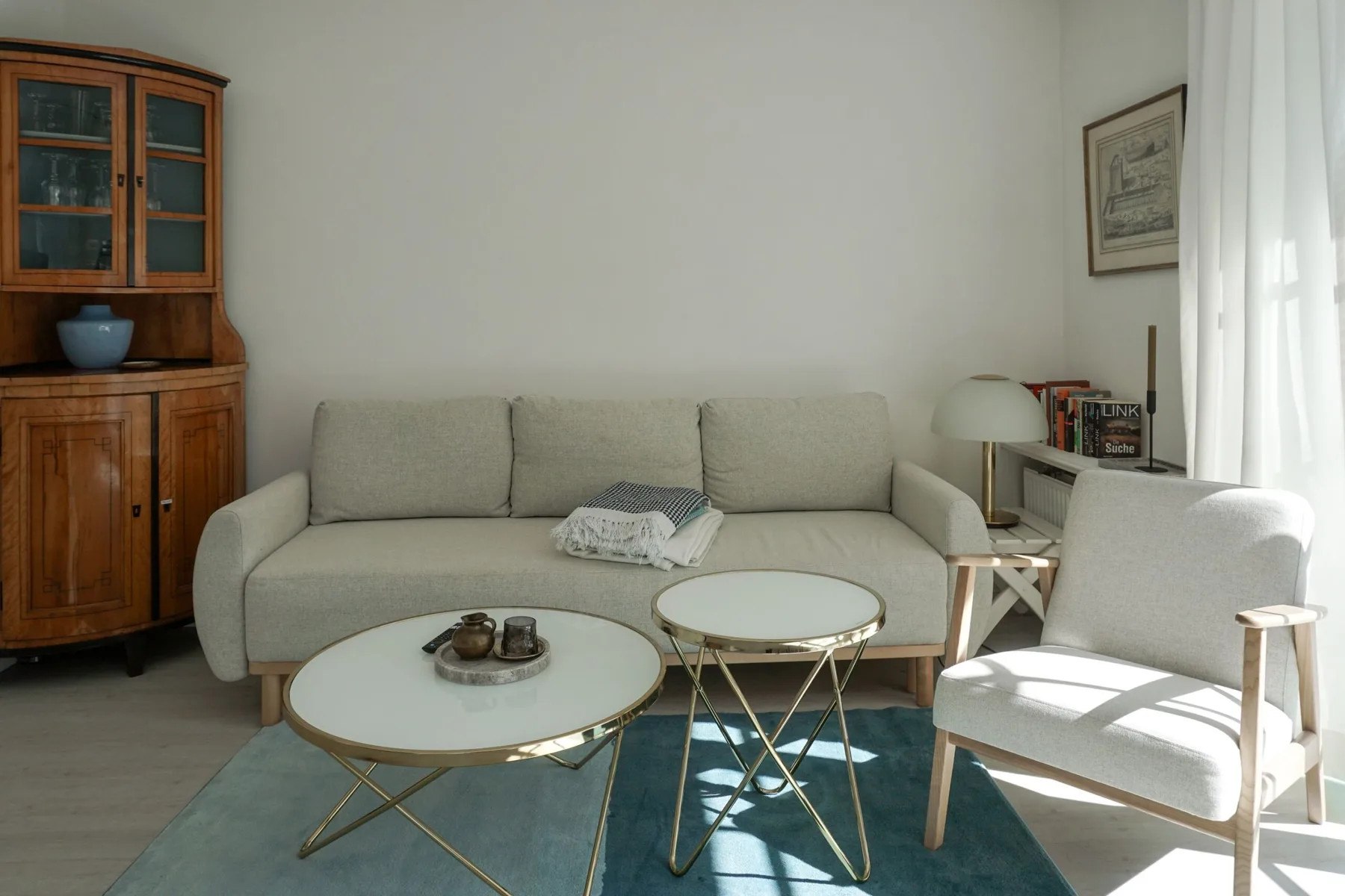 Una sala de estar con un sofá, un sillón y mesas de centro de vidrio.