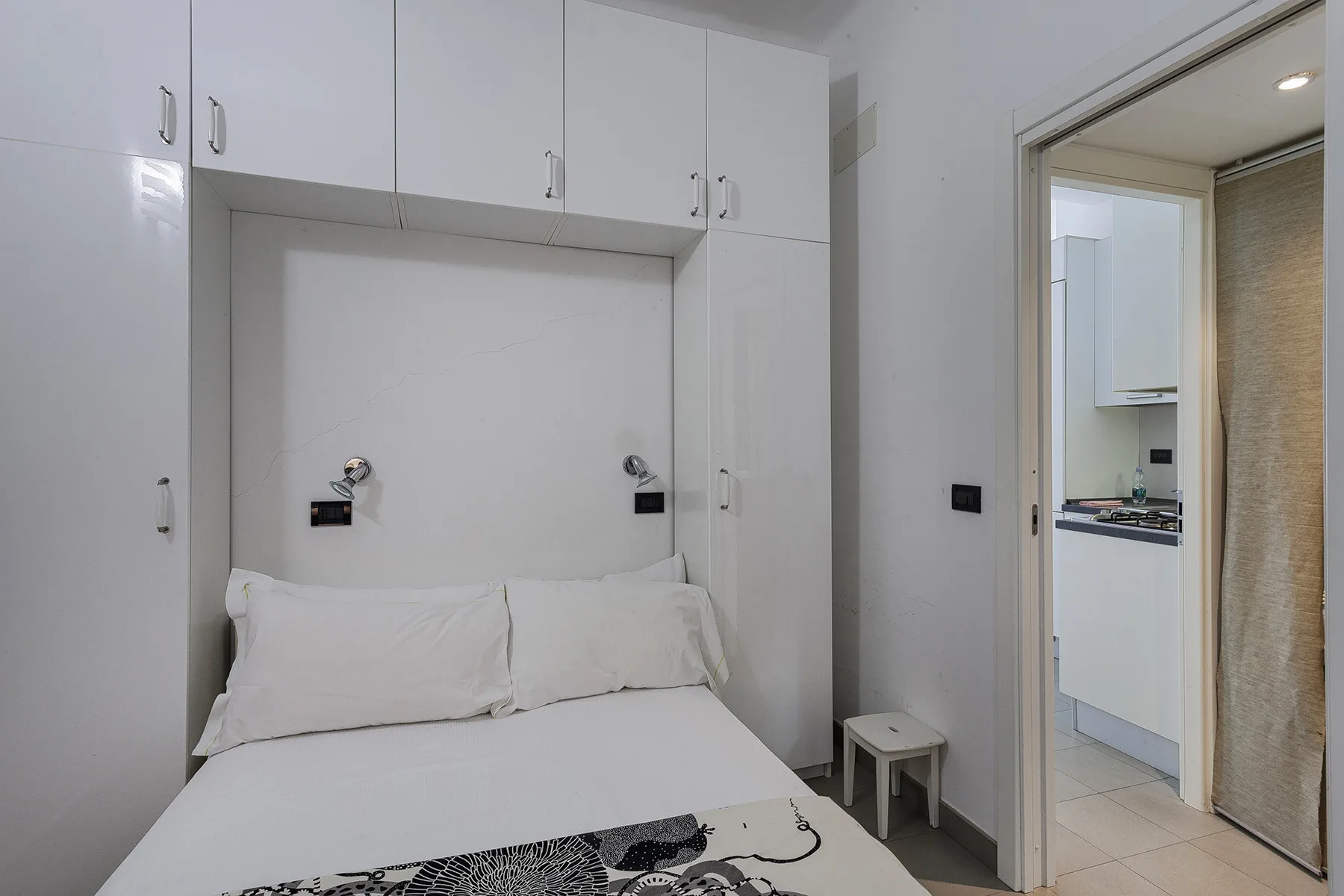 Un dormitorio con ropa de cama blanca bajo armarios empotrados.