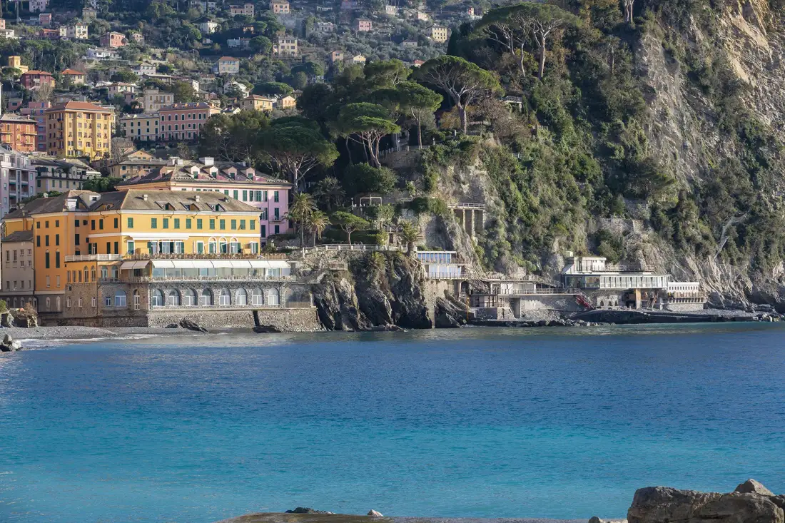 Un pueblo costero se alza sobre una bahía azul, con edificios agrupados en la ladera.