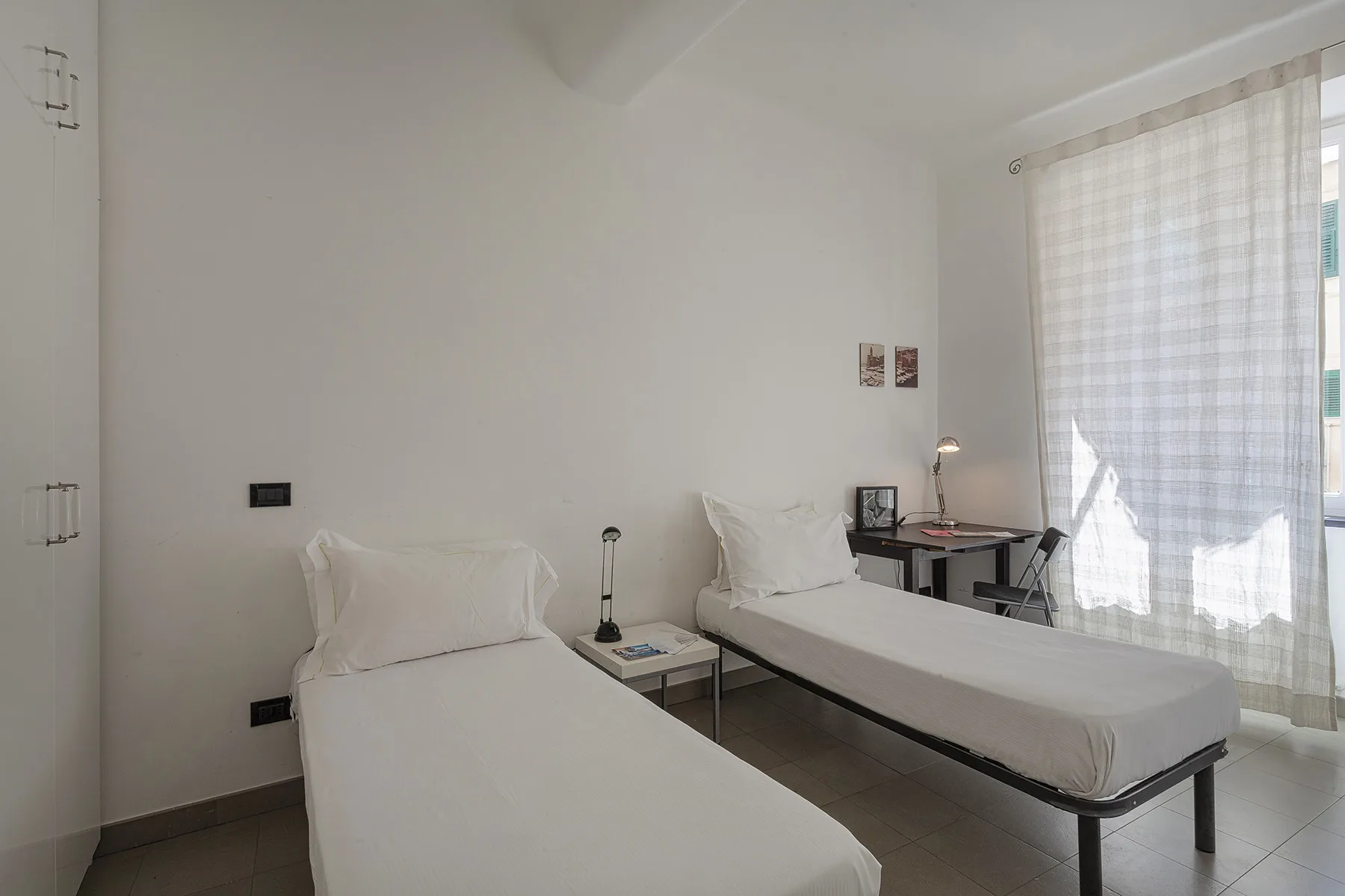 Un dormitorio luminoso con dos camas individuales junto a una ventana grande.