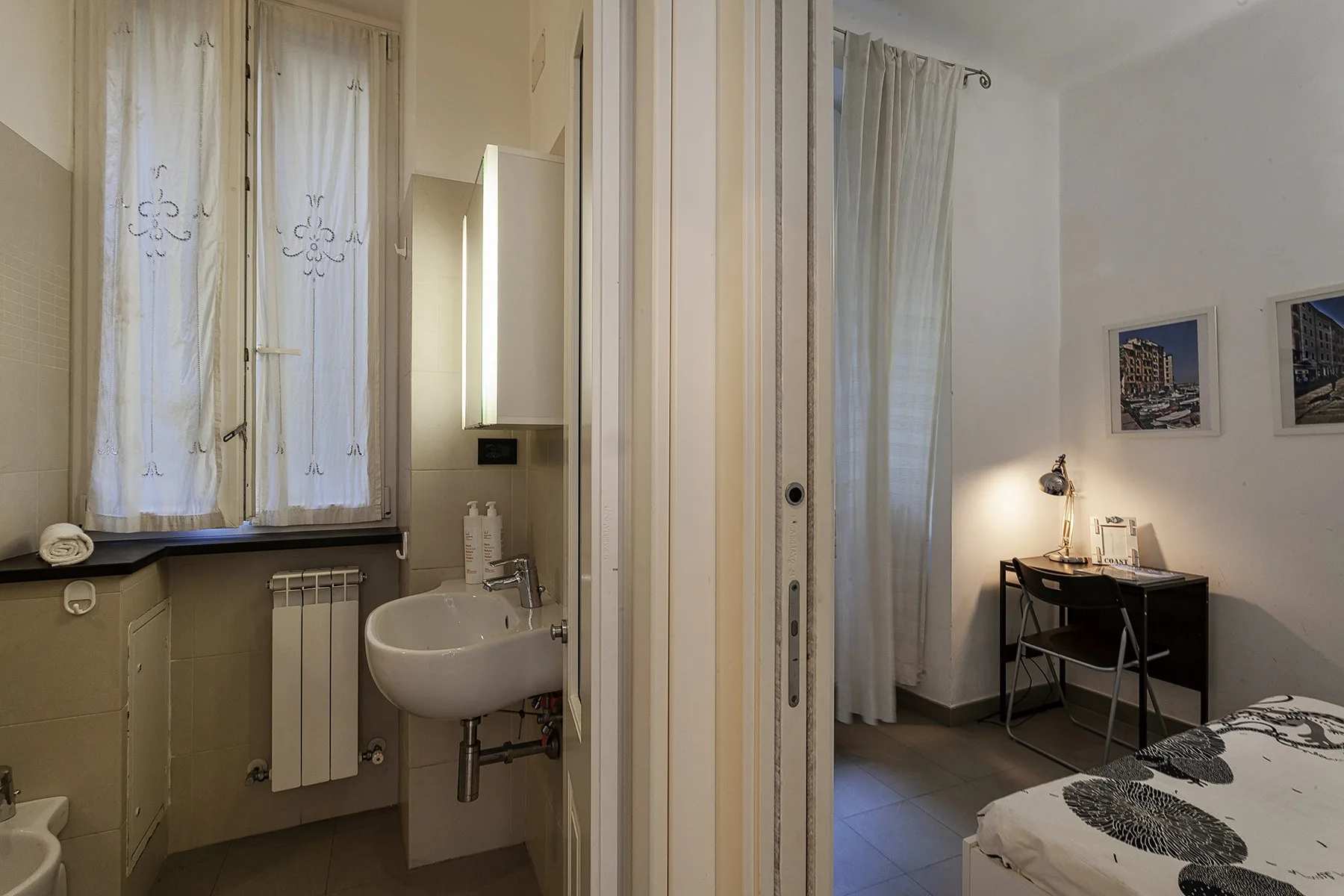 Un dormitorio con un escritorio junto a la cama y un baño contiguo con lavabo.
