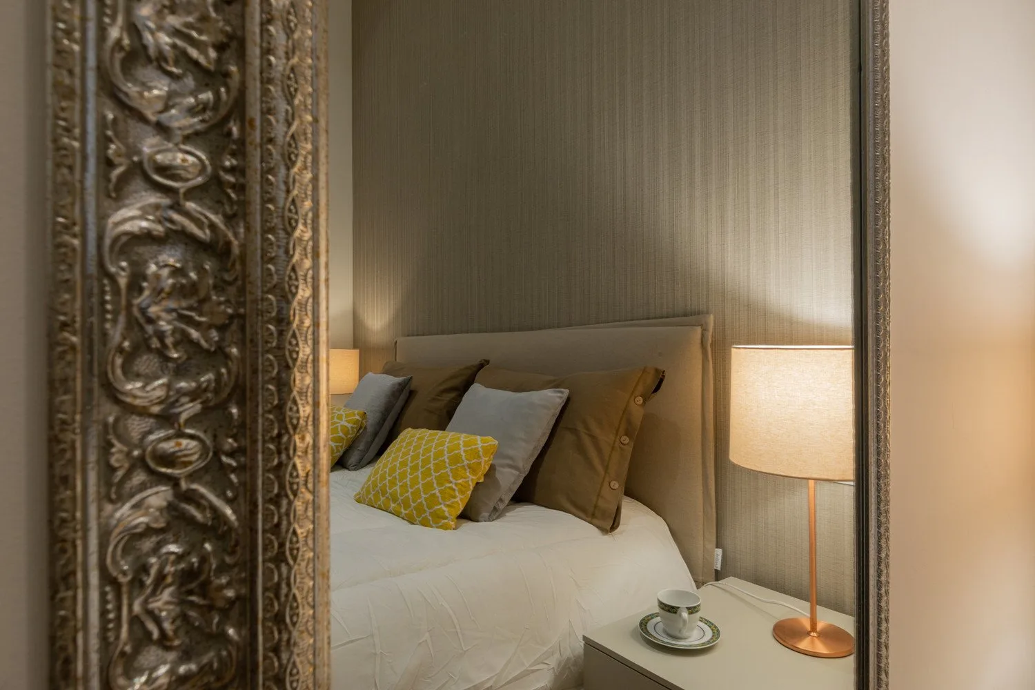 Un dormitorio con una cama bien hecha y una lámpara de noche encendida.