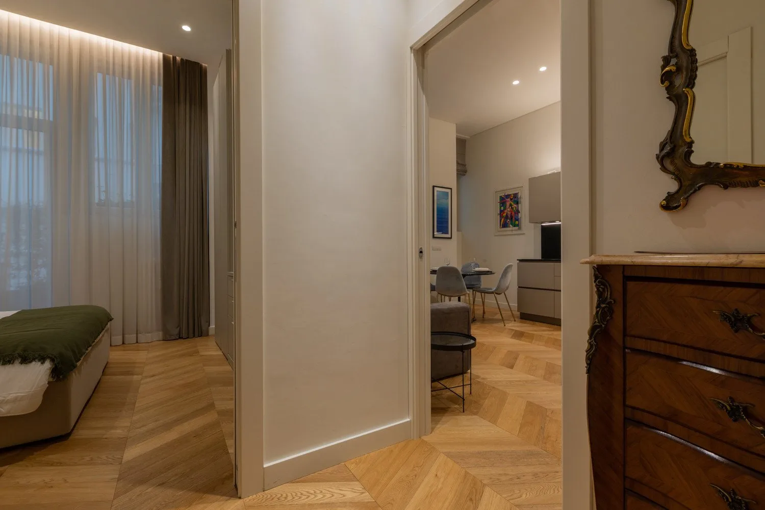 Un dormitorio se abre a un comedor con mesa y sillas.