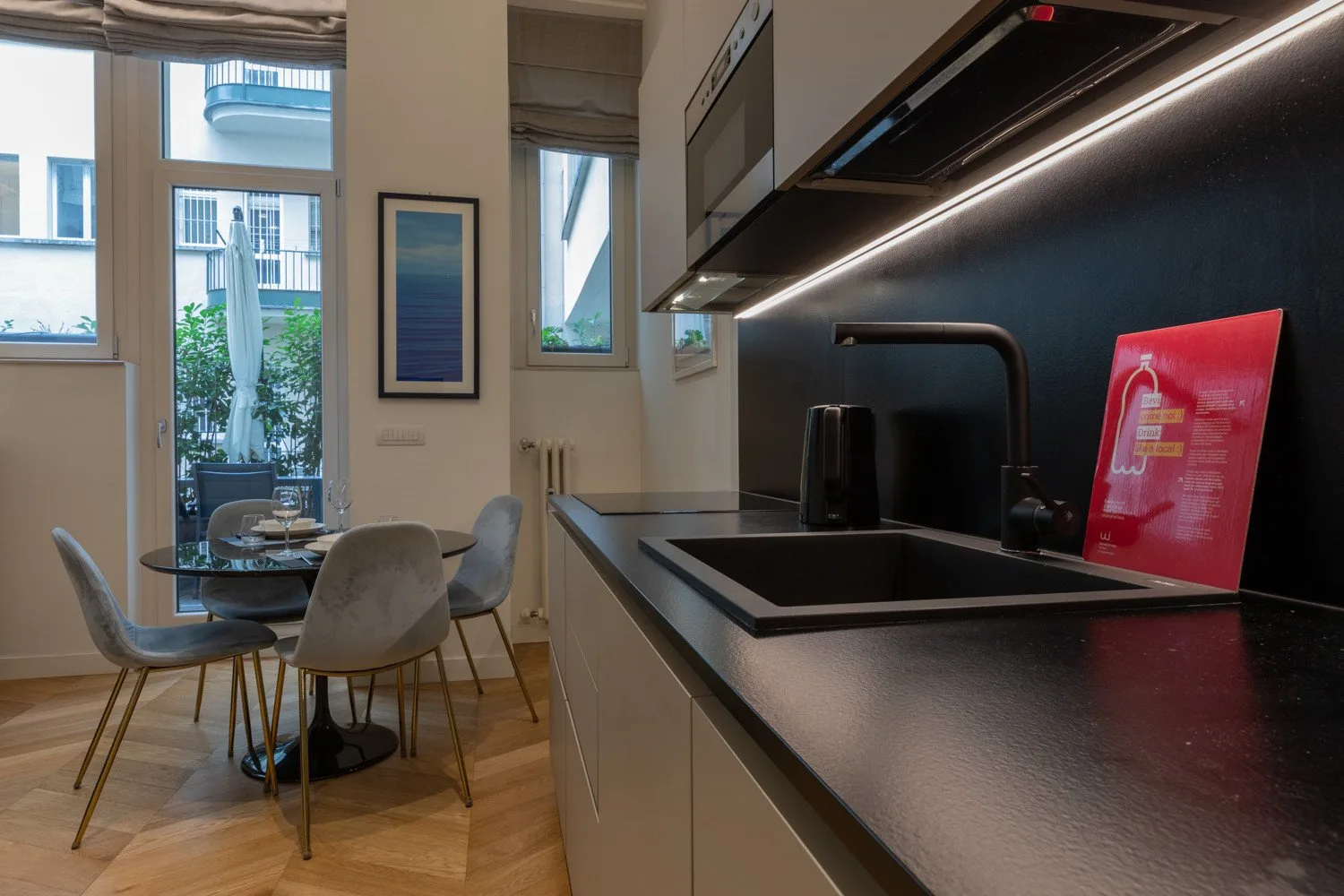 Una cocina moderna con una mesa de comedor junto a ventanas altas.