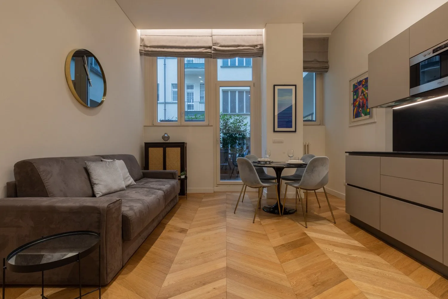 Una zona de estar y comedor con sofá, mesa y ventanas grandes.