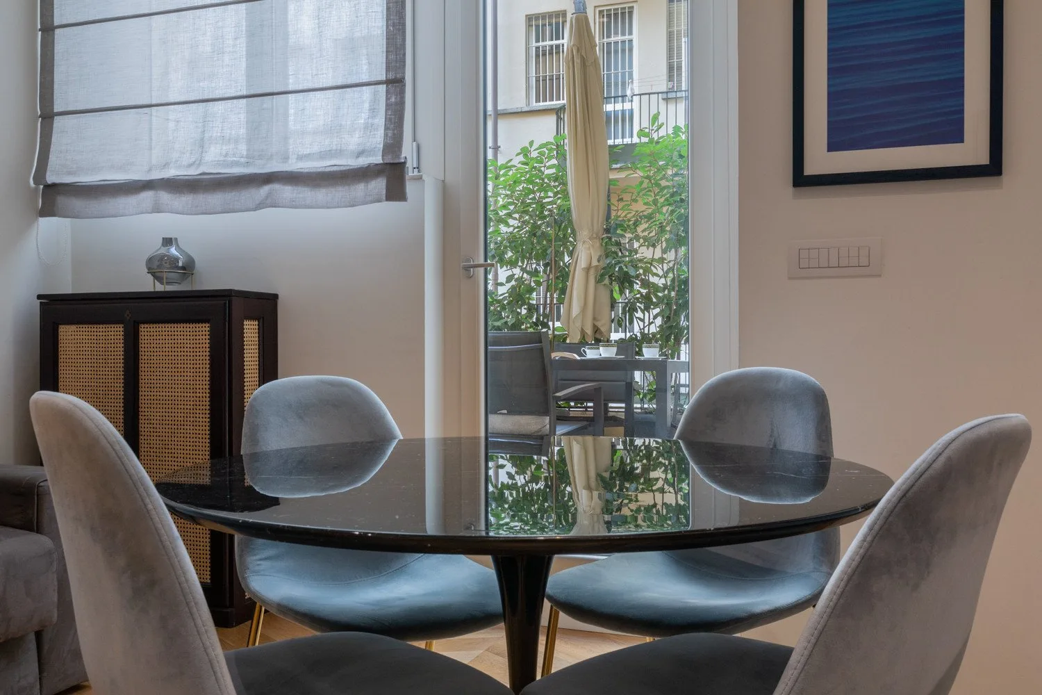 Un comedor con una mesa redonda y asientos tapizados junto a una puerta de vidrio.