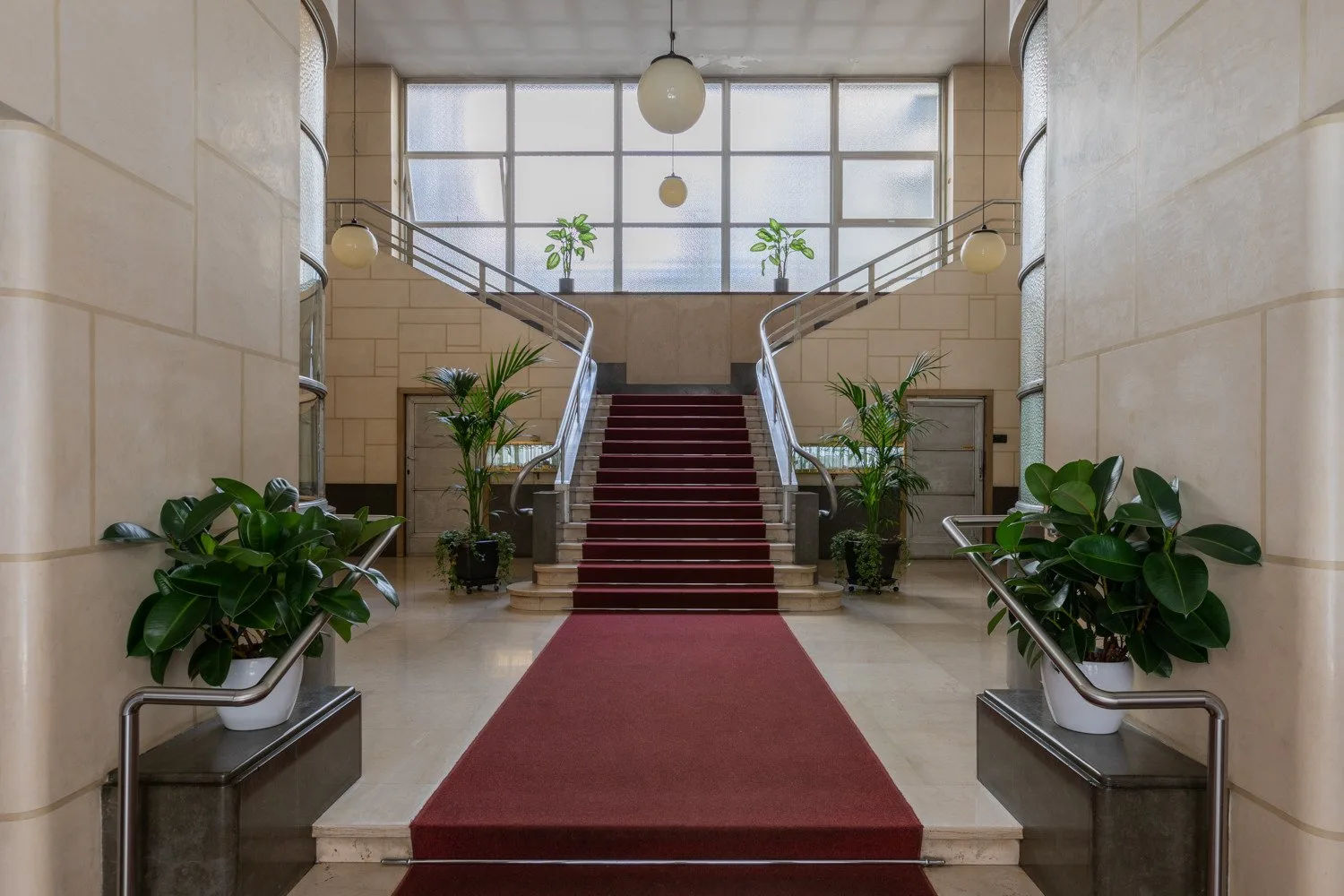 Un amplio vestíbulo con una alfombra roja que conduce a una escalera central.