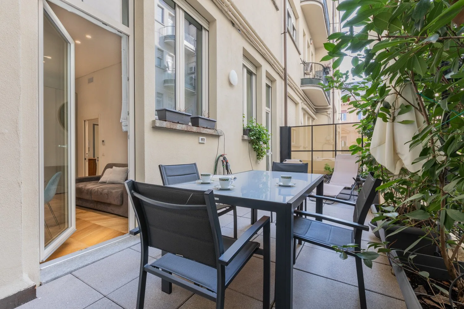 Un patio amueblado con una mesa de comedor y sillas junto a una puerta de vidrio abierta.