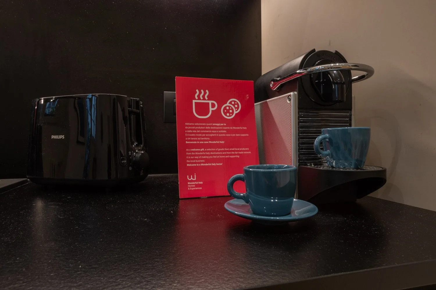 Una estación de café con cafetera, hervidor y tazas sobre una encimera.