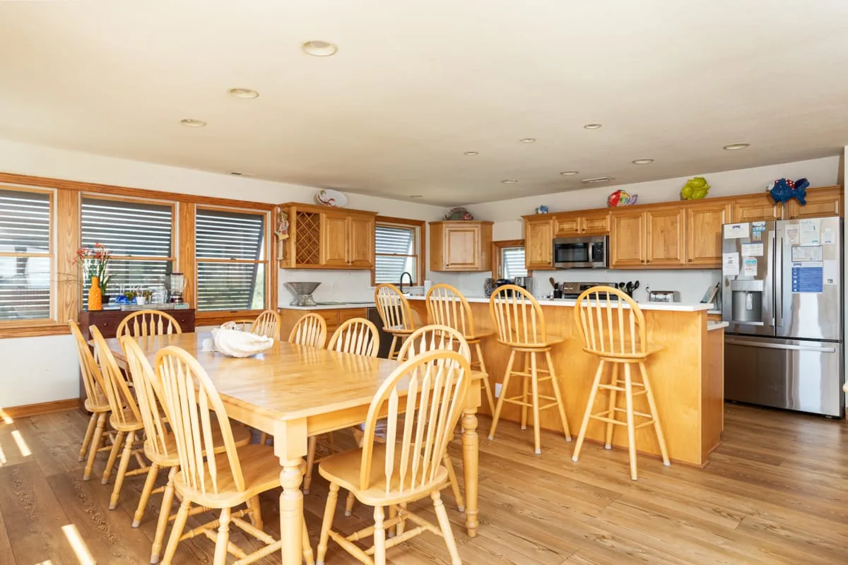 Una amplia cocina y comedor con una mesa de madera y una barra.