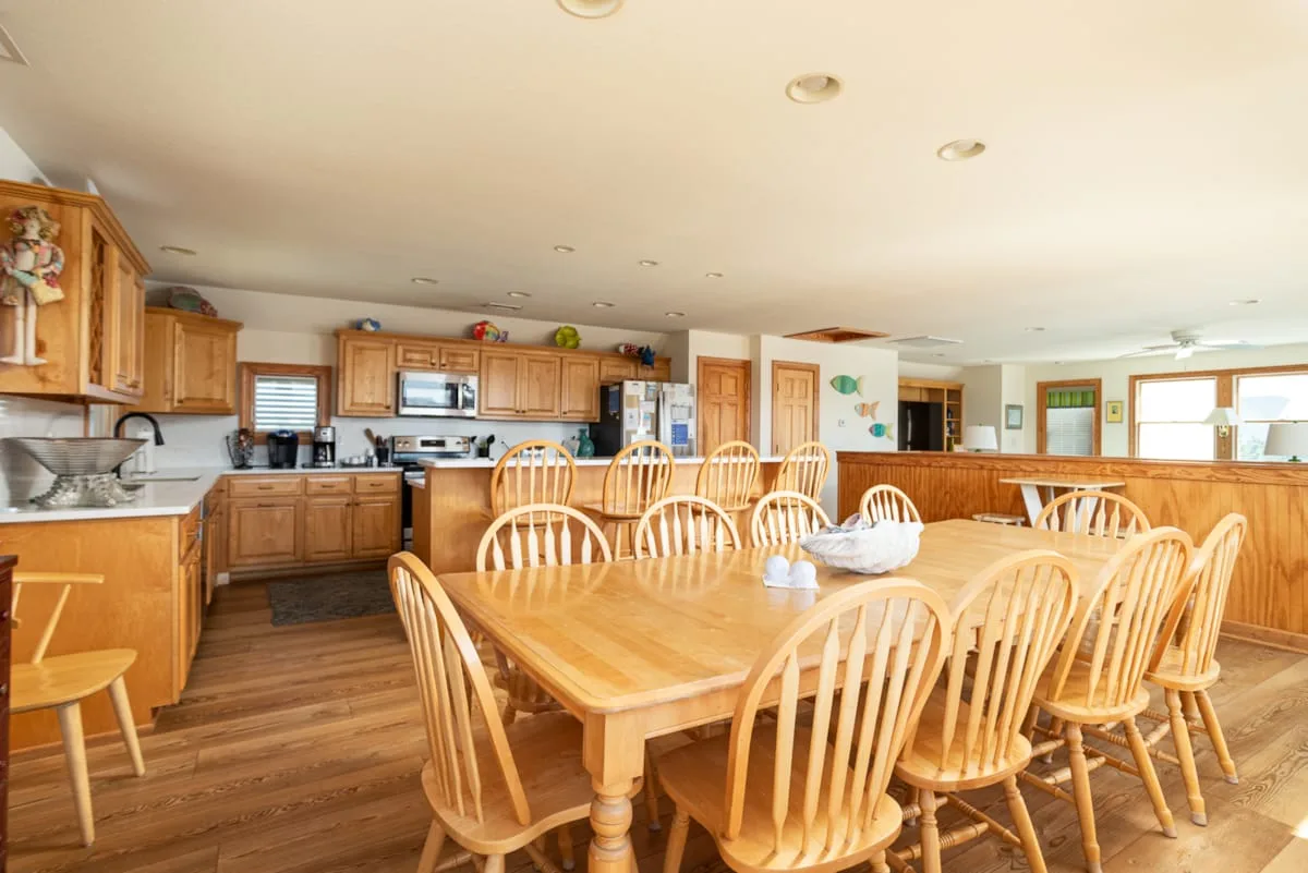 Un comedor amplio con una mesa larga de madera y sillas junto a la cocina.