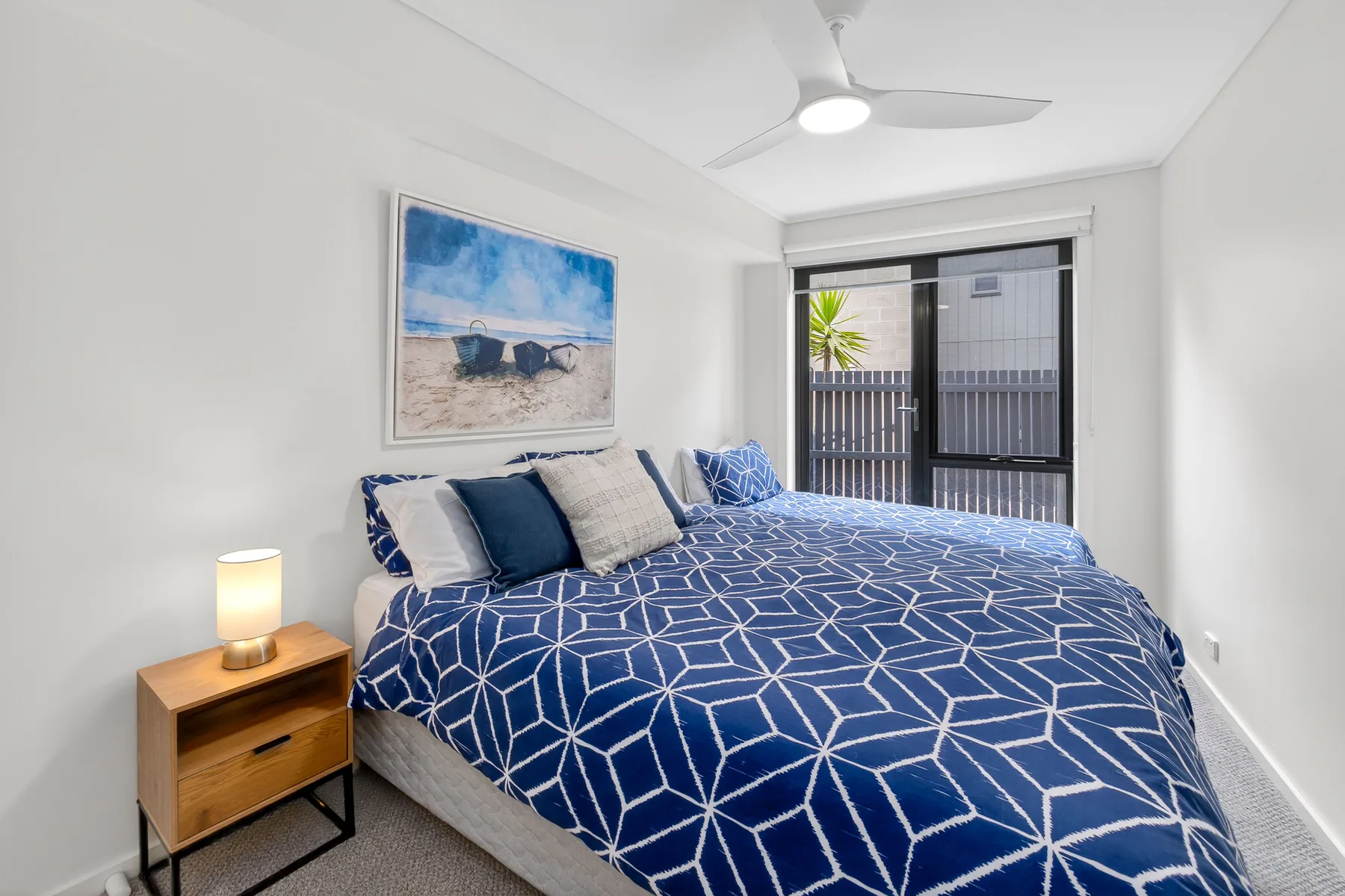 Dormitorio con una cama cubierta con ropa de cama azul de diseño geométrico.