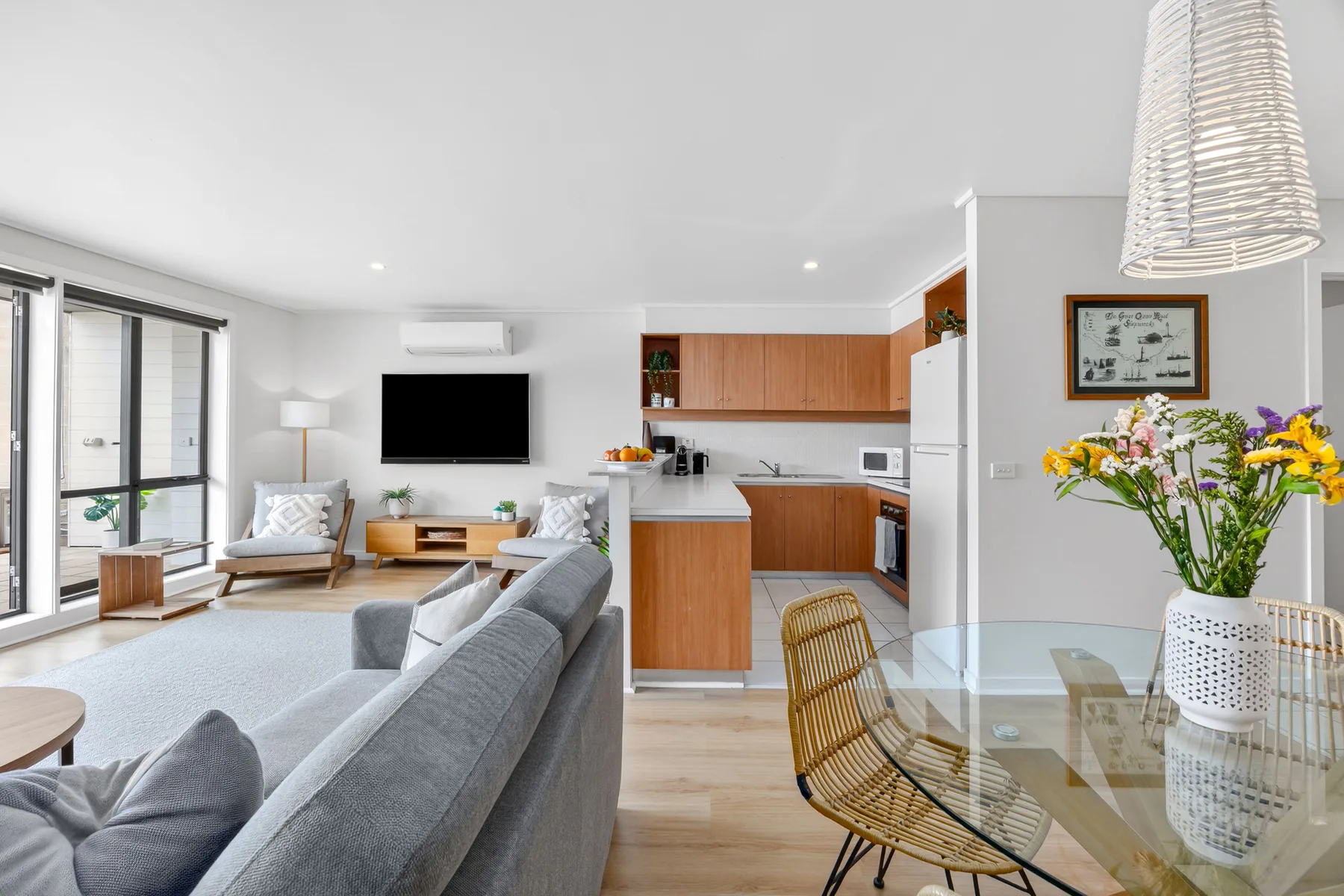 Una luminosa sala de estar y cocina de planta abierta, con mesa de comedor y grandes ventanas.