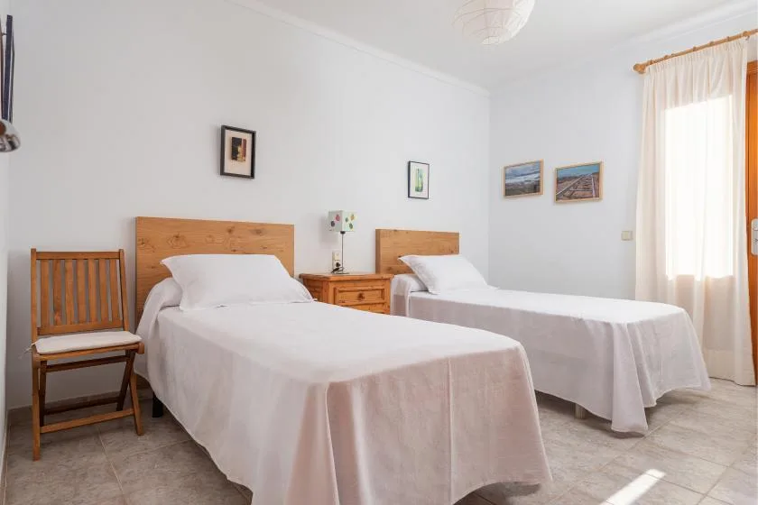 Un dormitorio con dos camas individuales bien tendidas y una mesita de madera.