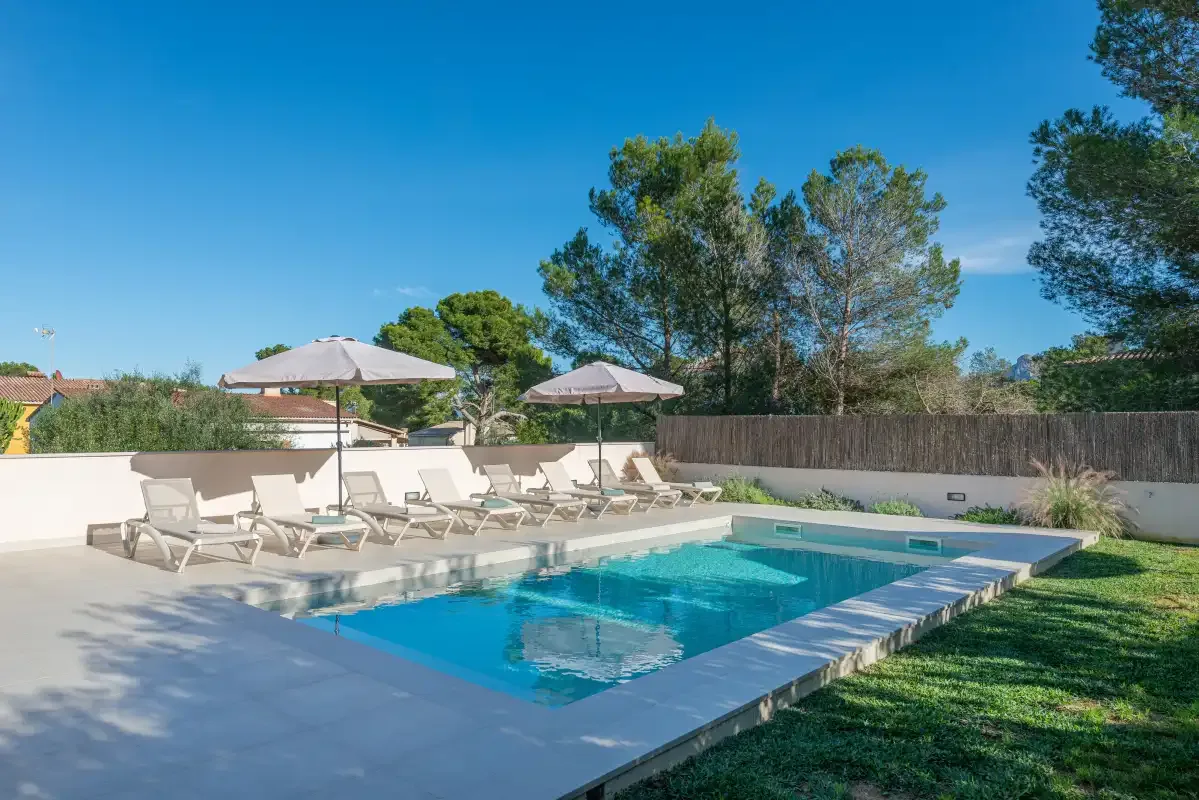 Una piscina al aire libre con asientos junto a una zona de césped.