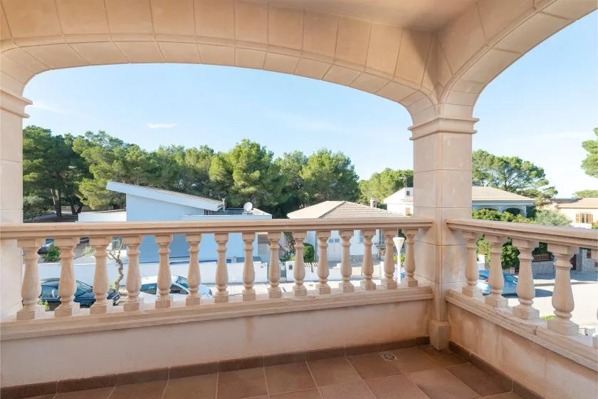 Una terraza exterior cubierta tiene vistas a árboles y edificios cercanos.