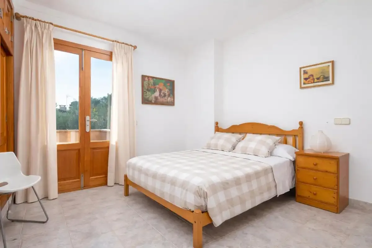 Un dormitorio con una cama de madera y puertas acristaladas que dan a un balcón.