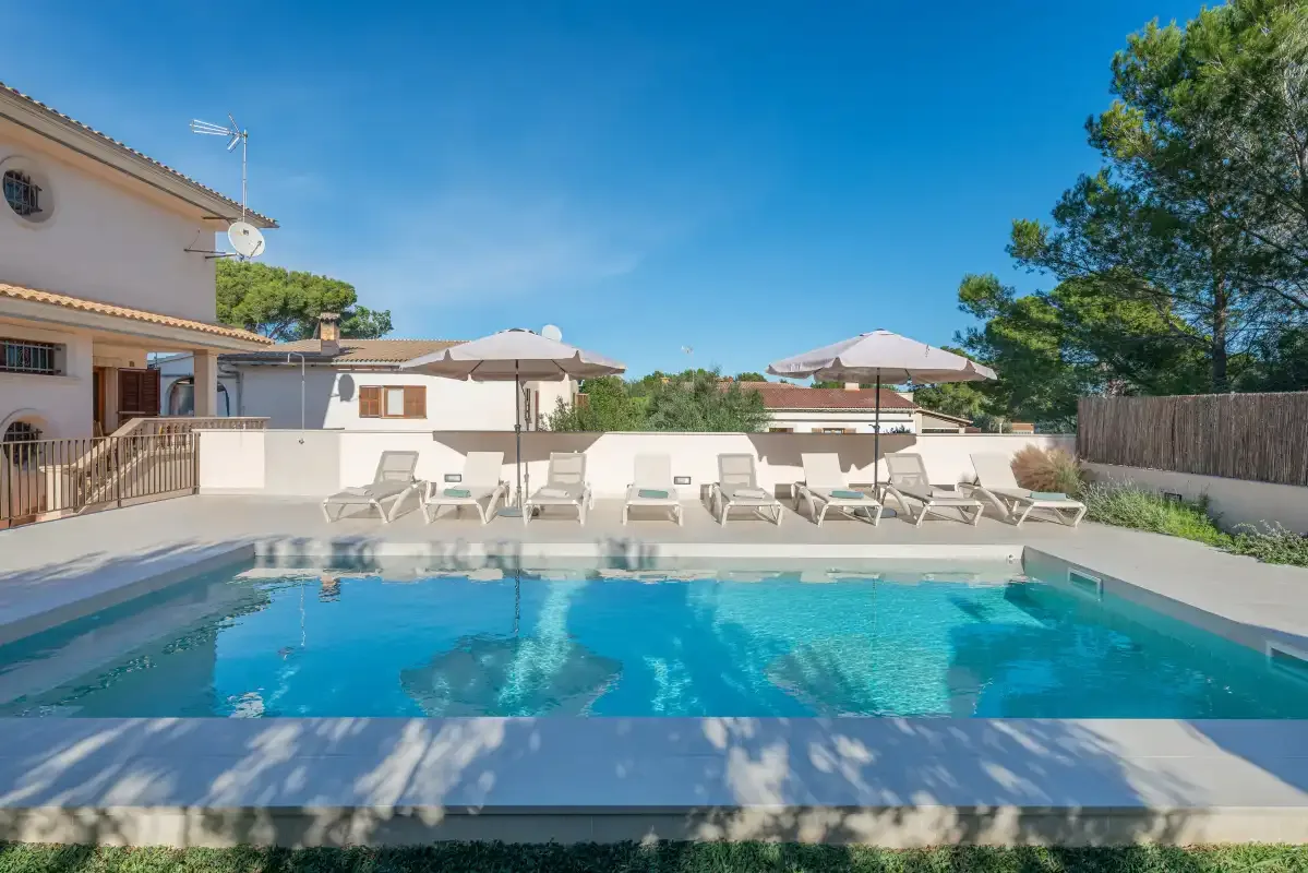 Una piscina al aire libre con asientos y sombrillas junto a un edificio.