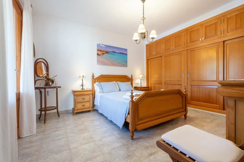 Un dormitorio con una cama de madera, armarios a juego y una imagen costera en la pared.