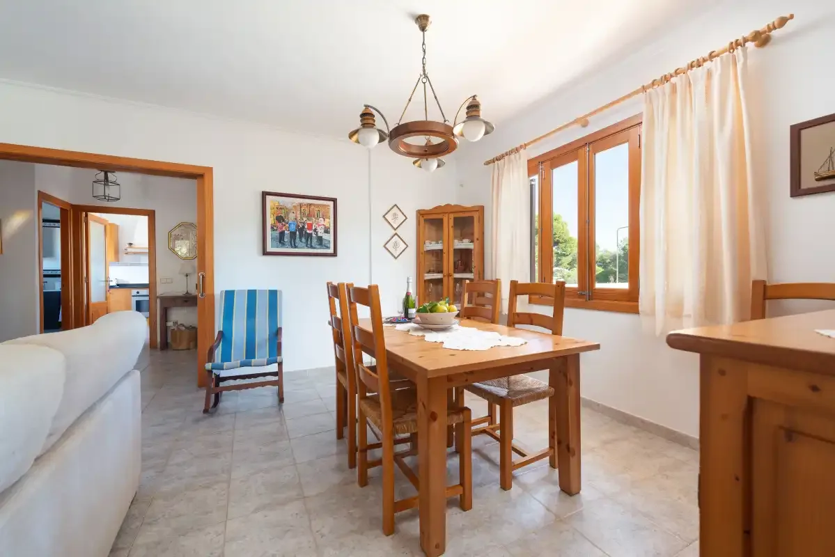 Comedor con una mesa de madera y sillas junto a grandes ventanas.